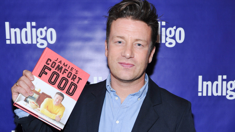 Chef Jamie Oliver posing with his book, "Jamie's Comfort Food"