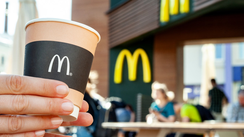 Hand holding a brown McDonald's coffee