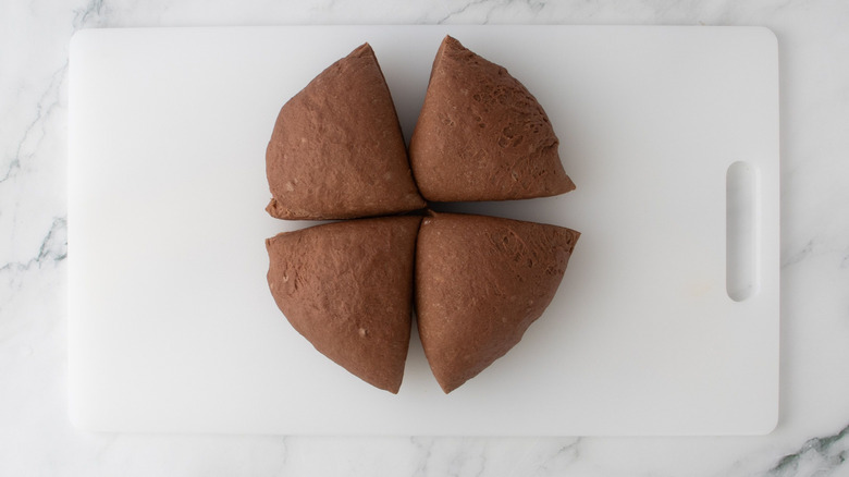 Brown bread dough cut into four pieces