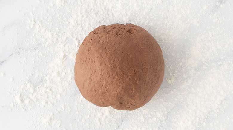 Brown bread dough ball on floured surface