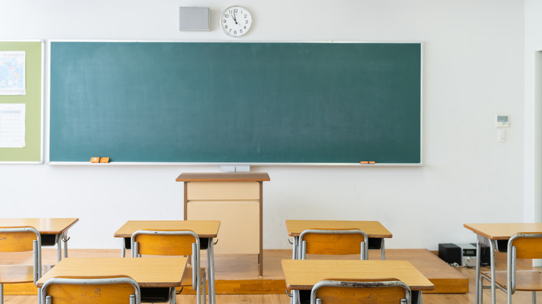 Empty high school classroom with wooden desks and green chalkboard