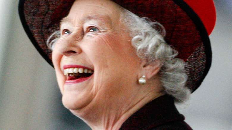 Queen Elizabeth II smiling in red hat