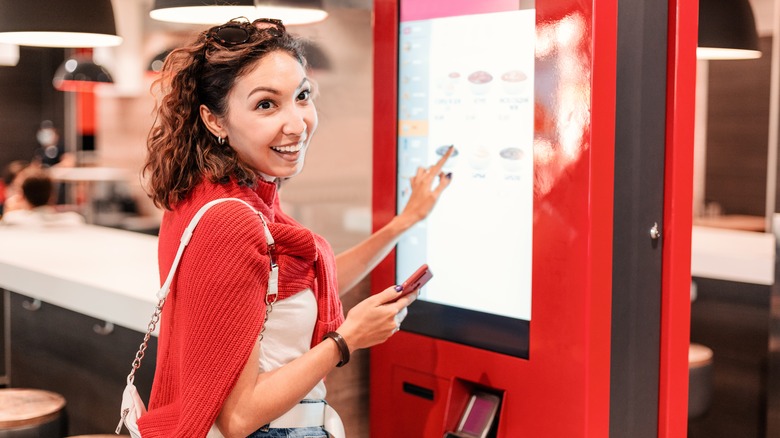 woman ordering fast food on self-service kiosk