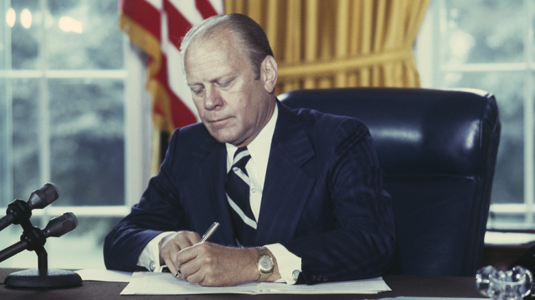 Gerald Ford signing document at desk