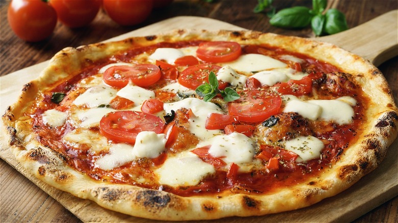 wood fired pizza topped with tomato slices and fresh mozzarella