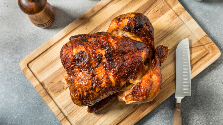 crispy rotisserie chicken on cutting board with knife