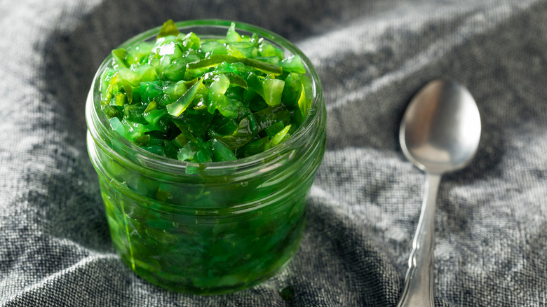Open jar of bright green relish with spoon