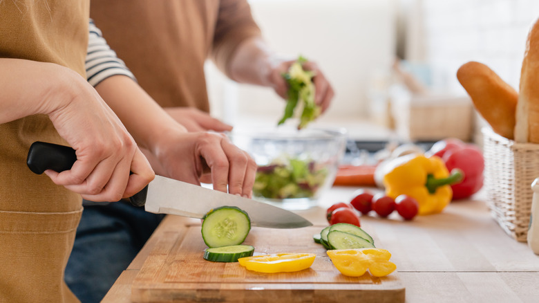 Hands holding a knife chopping vegetables on a cutting board