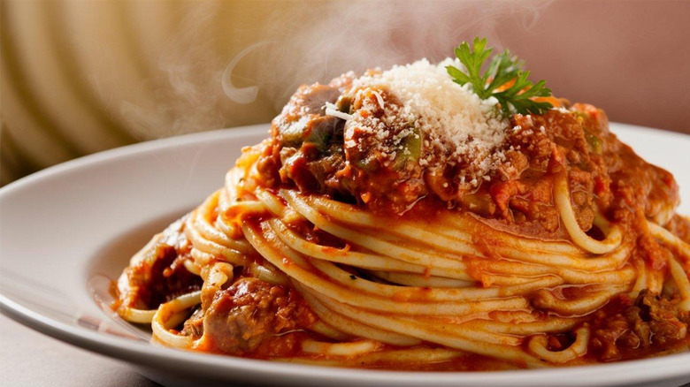 plate of spaghetti and marinara sauce garnished with parmesan cheese and basil