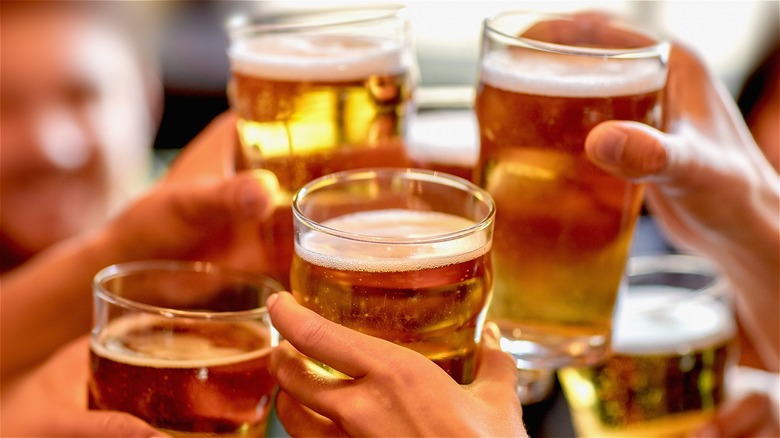 hands raising beer glasses in a toast