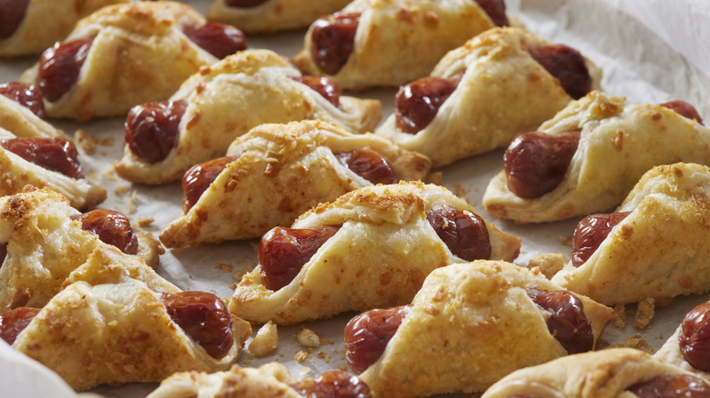A tray of baked pigs in a blanket on parchment paper