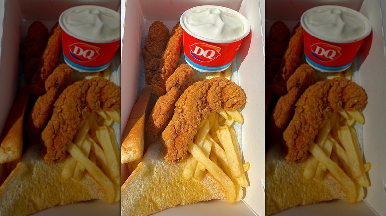 A carton filled with four chicken strips, french fries, two slices of Texas toast, and a side of soft serve.