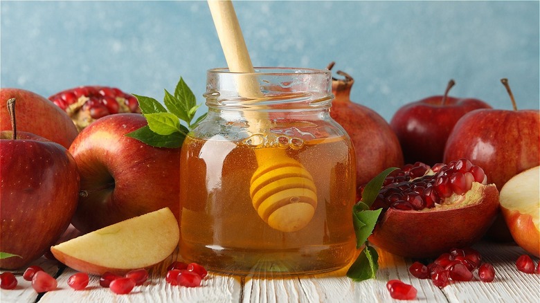 Rosh Hashanah spread of halved and whole apples and pomegranates and honey 