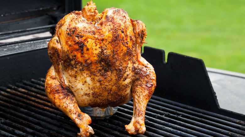 Beer can chicken cooking on a grill