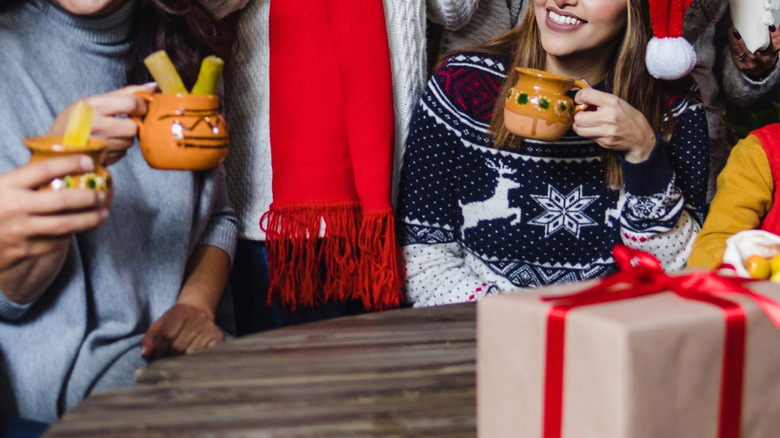 Mexican family celebrating Christmas with gifts and festive drinks in clay mugs
