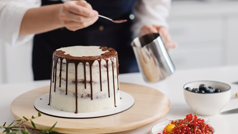 pastry chef decorating a cake with melted chocolate