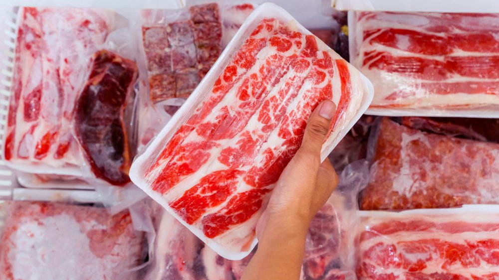 hand grabbing frozen meat from freezer