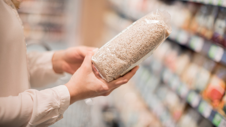 Woman holding bag of rice in grocery store