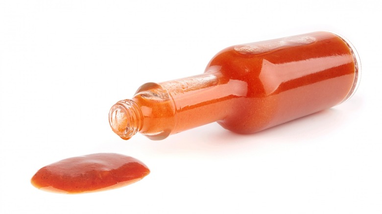 Hot sauce bottle laying on its side sauce dripping out