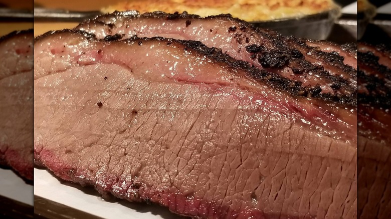 A close-up of a piece of juicy brisket with a dark bark and a pink smoke ring