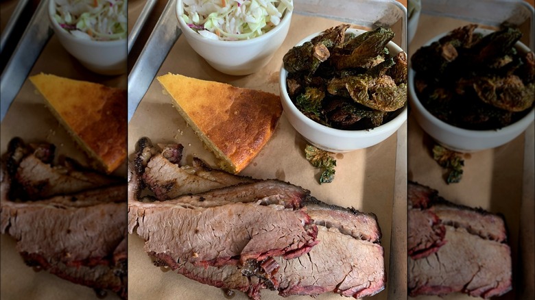 A barbecue tray with sliced brisket with a pink smoke ring served with a wedge of cornbread, a bowl of coleslaw, and a side of crispy fried Brussels sprouts