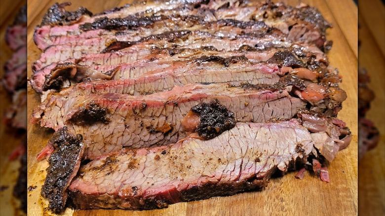 Several slices of juicy and marbled brisket on a wooden cutting board