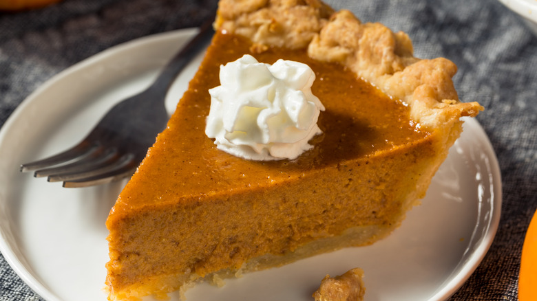 Slice of pumpkin pie with whipped cream on top