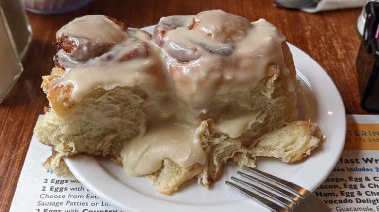 Two large Ann Sather cinnamon rolls on plate with fork