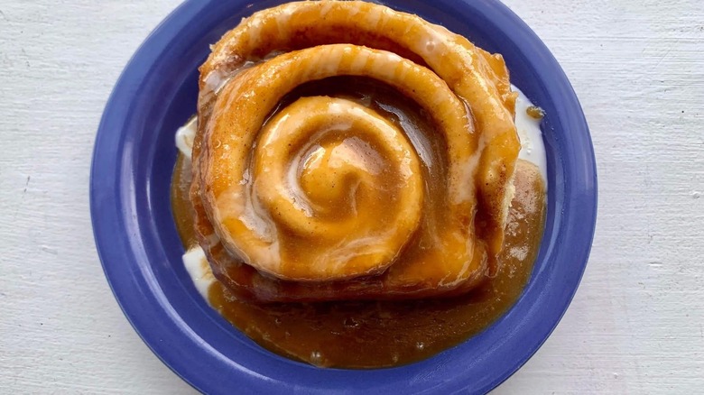 A glazed cinnamon roll on a blue plate