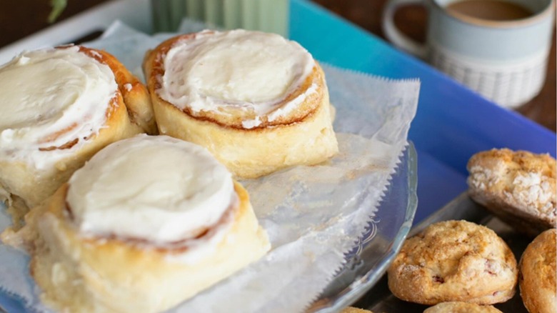 Three frosted cinnamon rolls from Counterspace next to plate of scones