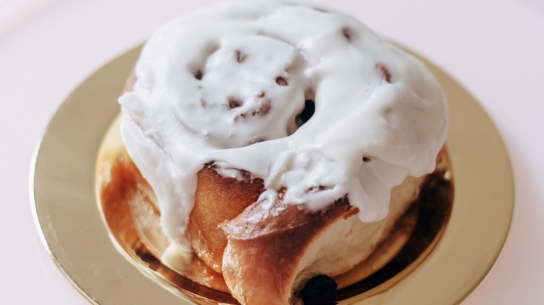 Frosted cinnamon roll on a gold plate