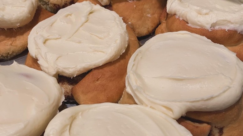 Rows of cinnamon rolls, topped with thick, creamy frosting