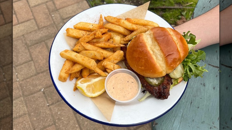 Fish sandwich on plate with fries and aioli