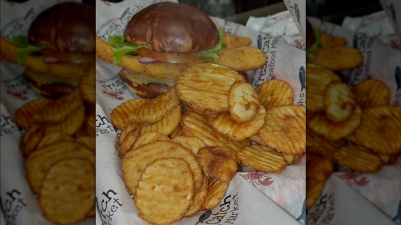 A fried fish sandwich on bun with fries in basket