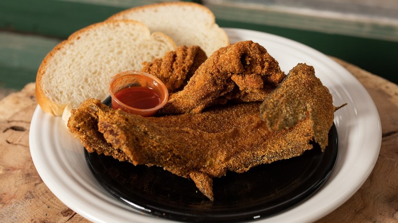 Fried fish on plate next to slices of white bread