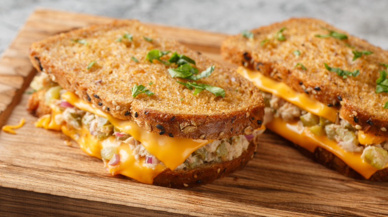 grilled tuna melt with cheese and parsely garnish on wooden board
