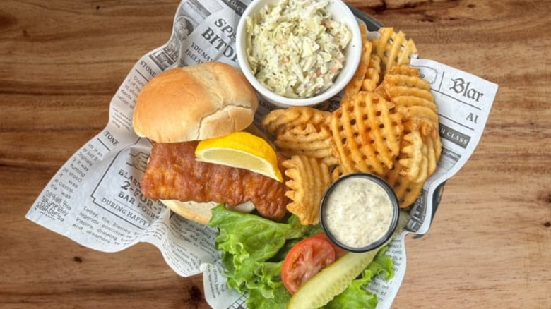 top down view of basket with fried fish sandwich and fries at restaurant