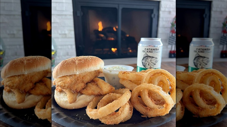 fish sandwich on sesame seed bun with onion rings and side of coleslaw
