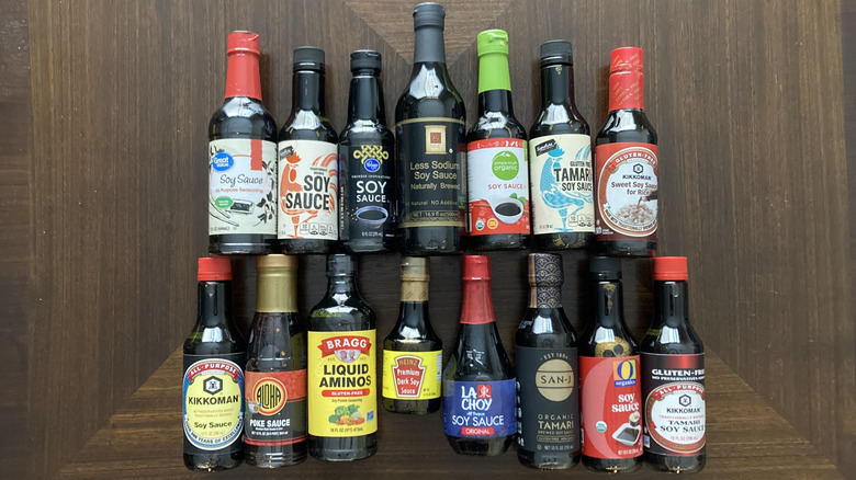 15 different bottles of soy sauce on wood background