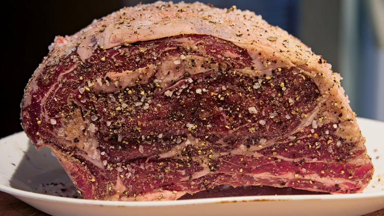 Raw prime rib generously seasoned