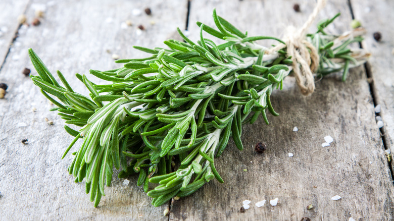 Rosemary bundle on wood table with flakes of seasonings