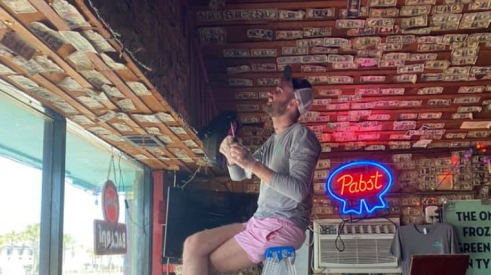 Man helping take down dollar bills at Sand Bar