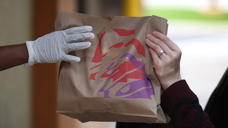 Taco Bell drive-thru worker handing over bag to customer