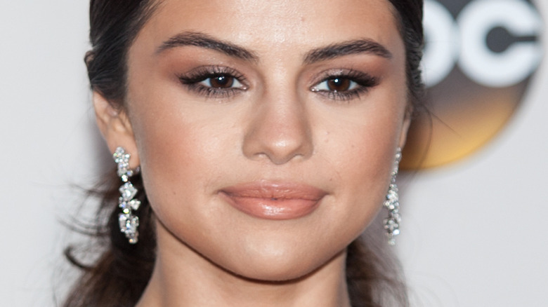 Selena Gomez smirking in dangly earrings