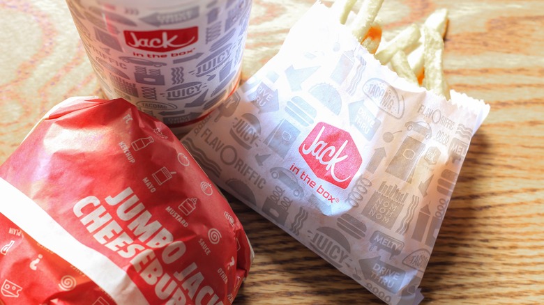 Jack in the Box burger, fries, and drink on wooden table