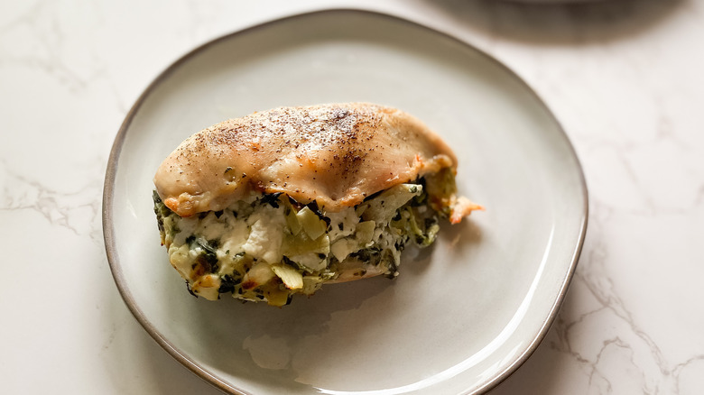 artichoke-stuffed chicken breast on ceramic plate