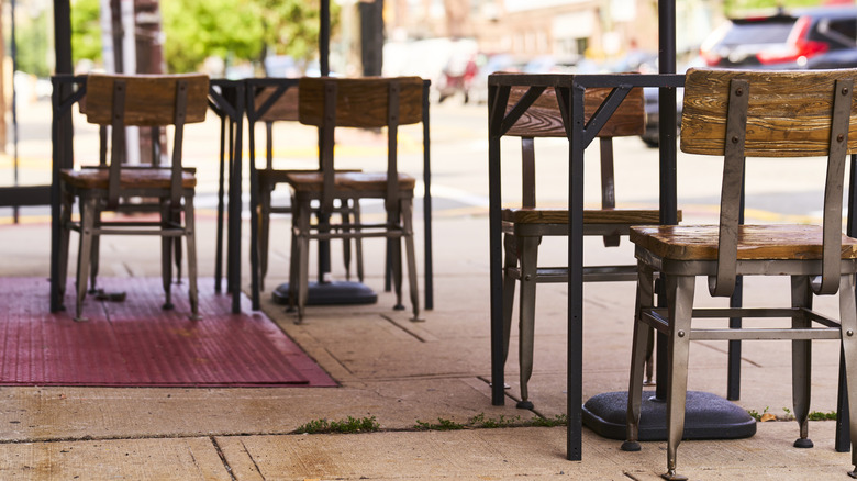 view of restaurant tables and chairs on an uneven sidewalk