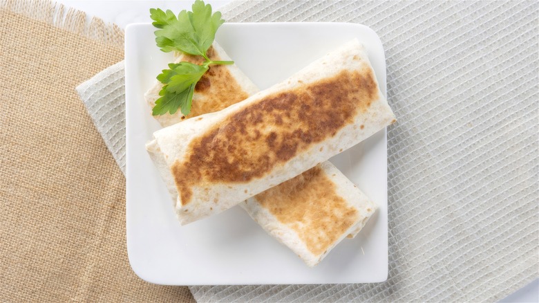 Freshly heated frozen breakfast burritos on a white plate.