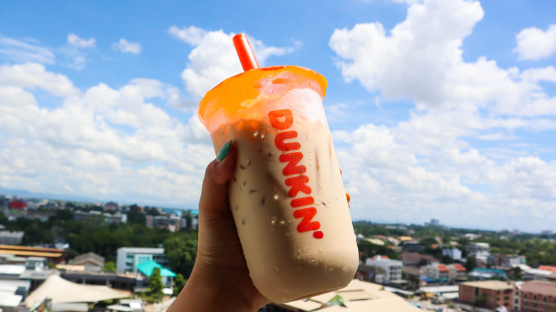 A hand holding a Dunkin' iced coffee in the air