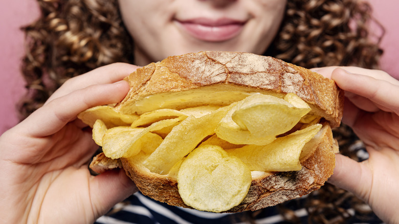 Person eating a potato chip sandwich